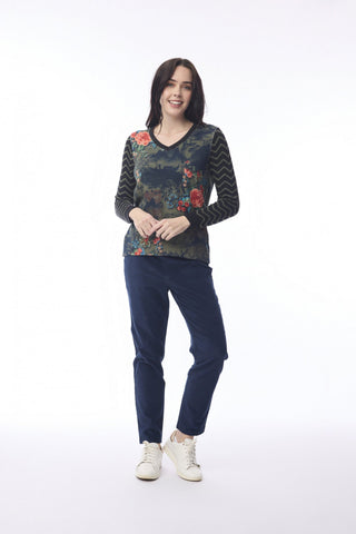 Woman wearing a floral print v-neck sweater with chevron sleeves and navy blue pants.
