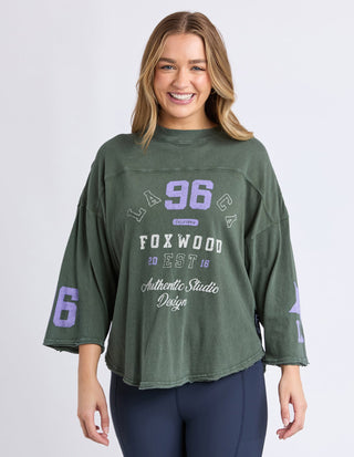 Woman wearing a green Foxwood oversized graphic sweatshirt with purple 96 print.