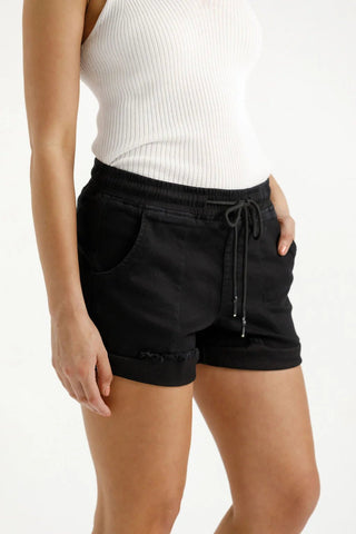 Woman wearing black drawstring casual shorts and a white ribbed tank top.