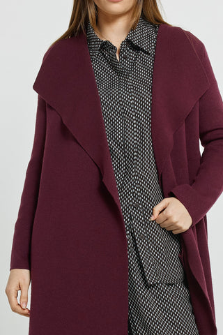 Woman wearing a burgundy open-front coatigan over a black and white patterned shirt
