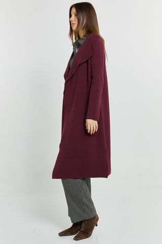 Woman wearing a long burgundy wool coat with polka dot trousers and brown suede boots