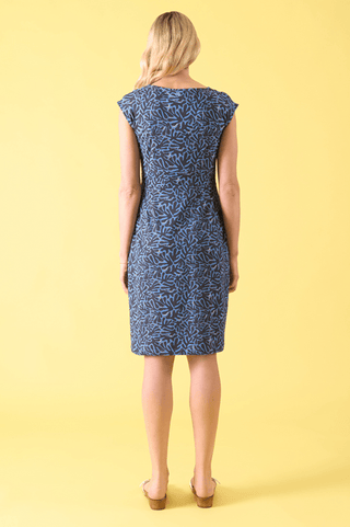 Back view of a woman wearing a navy blue and light blue patterned knee-length dress.