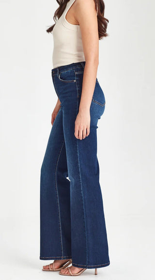 Woman wearing a white ribbed tank top and dark blue wide-leg denim jeans.