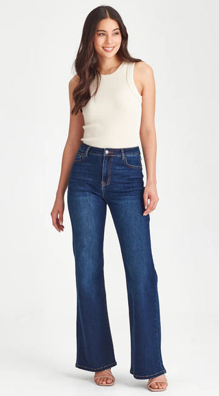 Woman wearing a cream ribbed sleeveless top and dark wash flare jeans.