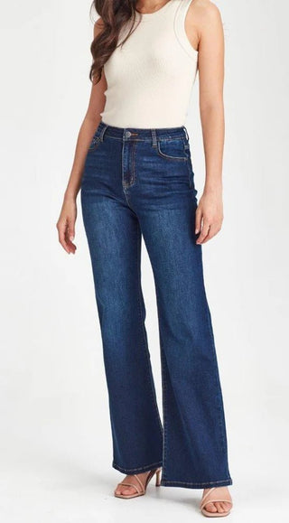 Woman wearing a white sleeveless top and dark blue wide-leg flare jeans.