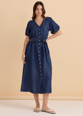 Woman wearing a navy blue denim midi dress with short puff sleeves and button-down front.