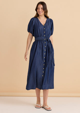Woman wearing a navy blue denim midi dress with short puff sleeves and button-down front.