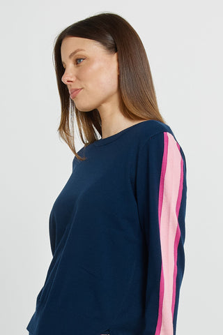 Woman wearing a navy blue long sleeve sweatshirt with pink side stripes.