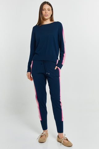 Woman wearing navy blue leisure wear set with pink side stripes and matching joggers.