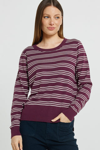 Woman wearing a maroon and white striped long sleeve sweatshirt and dark blue pants.