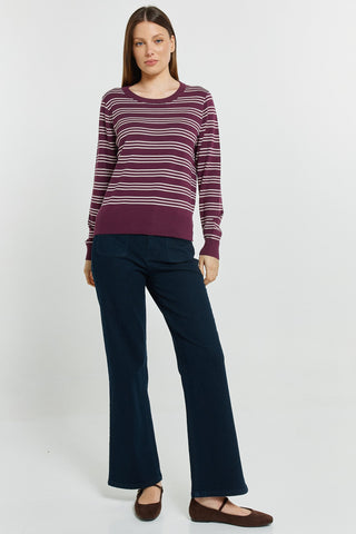 Woman wearing a maroon striped long sleeve sweatshirt and dark navy flare pants.