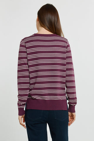 Woman wearing a burgundy and white striped long sleeve sweatshirt and dark denim jeans.
