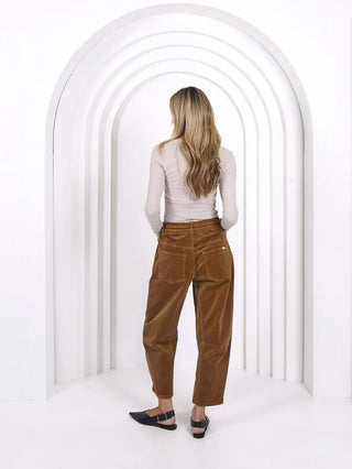 Woman wearing beige long sleeve top and brown corduroy wide leg pants.
