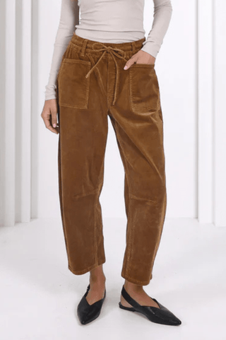 Woman wearing brown corduroy drawstring trousers and black pointed flats.