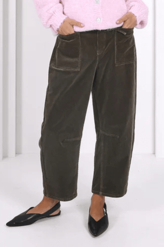 Woman wearing olive green corduroy wide-leg pants with large front pockets and black flats.