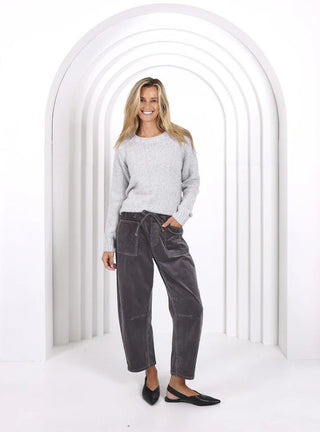 Woman wearing a grey knit sweatshirt and dark grey lounge pants with black flats.