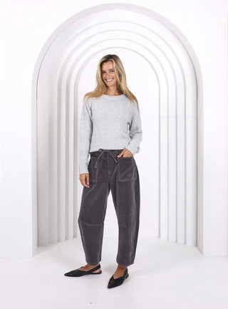 Woman wearing a grey knit sweater and charcoal grey drawstring lounge pants with black flats.