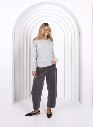 Woman smiling in a grey knit sweater and charcoal wide-leg lounge pants.
