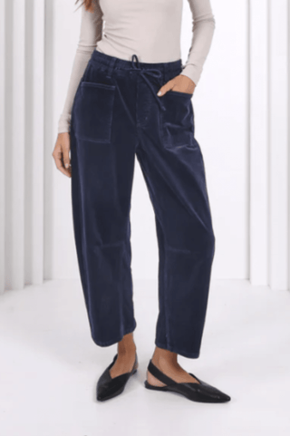 Woman wearing navy blue velvet drawstring pants and black pointed flats