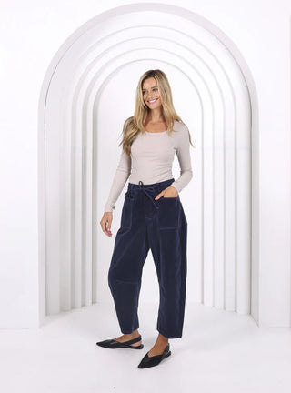 Woman wearing a beige long-sleeve top and navy blue drawstring apartment pants.