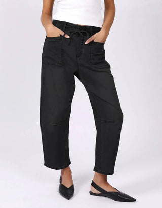 Woman wearing black high-waisted cropped trousers with a drawstring waist and utility pockets.