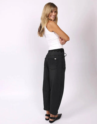 Woman wearing black wide-leg trousers and a white sleeveless tank top.