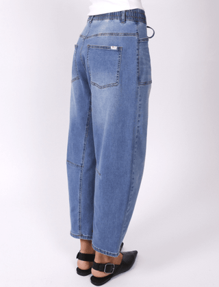 Woman wearing high-waisted blue denim wide-leg pants and black platform sandals.