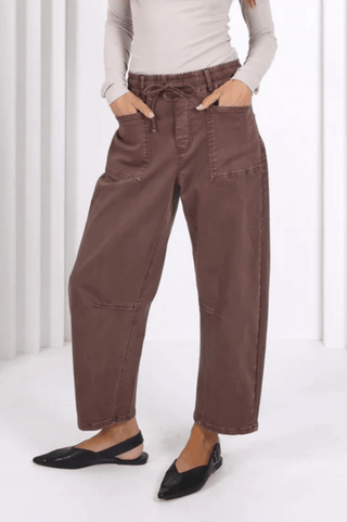 Woman wearing brown high-waisted wide leg utility pants and black pointed flats.