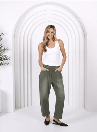 Woman wearing a white tank top and olive green wide-leg apartment pants.