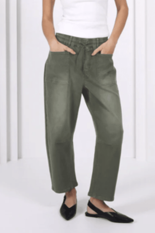 Woman wearing olive green wide-leg lounge pants and black pointed flats.