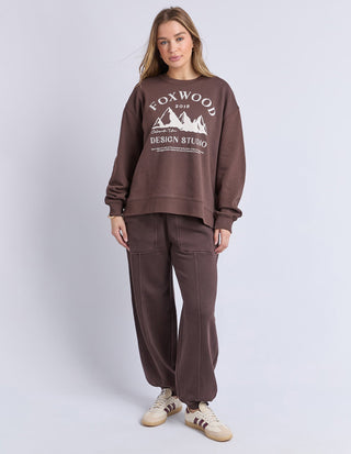 Woman wearing a brown Foxwood design studio sweatshirt and matching wide-leg lounge pants.