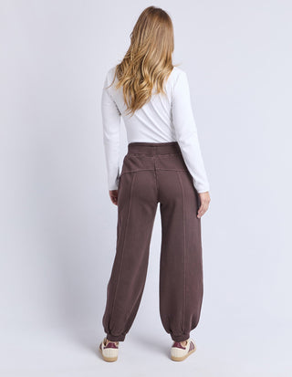 Woman wearing a white long-sleeve top and brown wide-leg lounge pants.