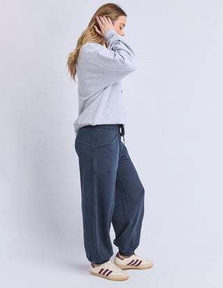 Woman wearing a grey sweatshirt, navy blue apartment pants, and white sneakers.