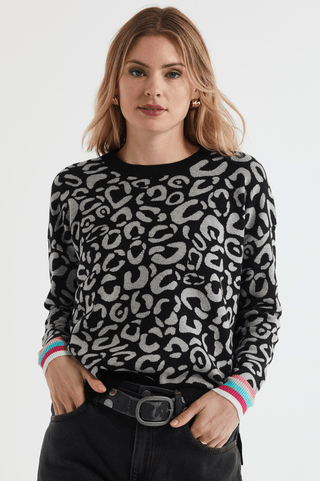 Woman wearing a black and grey leopard print sweater with colourful striped cuffs.