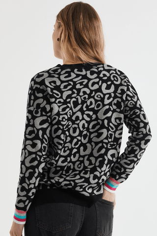 Woman from behind wearing a black and grey leopard print sweatshirt with colorful cuffs.