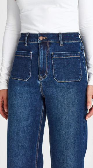Woman wearing high-waisted dark blue denim jeans with front patch pockets.