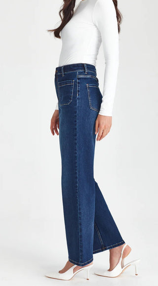 Woman wearing high-waisted dark blue straight-leg jeans and a white long-sleeve top.