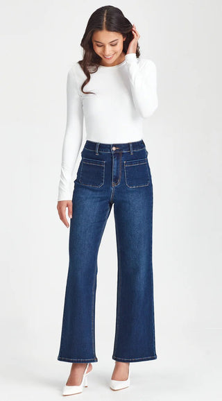Woman wearing white long sleeve top and dark blue wide leg denim jeans.
