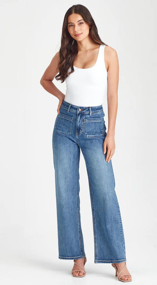 Woman wearing a white tank top and blue wide-leg denim jeans