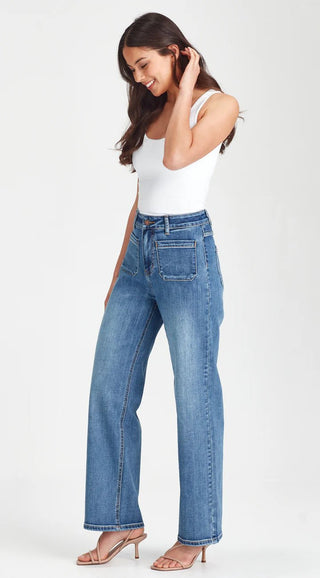 Woman wearing high-waisted blue wide-leg denim jeans and a white tank top.