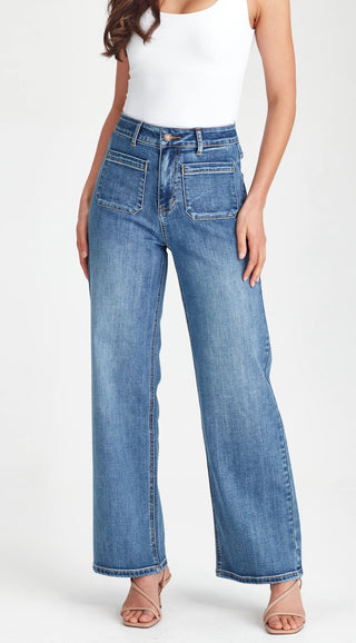 Woman wearing high-waisted blue wide-leg denim jeans and a white tank top.