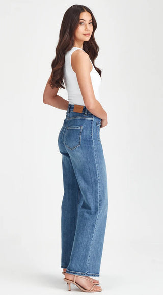 Woman wearing a white sleeveless top and blue wide-leg denim jeans.