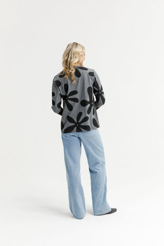 Woman from behind wearing a grey oversized floral print sweatshirt and light blue wide-leg jeans