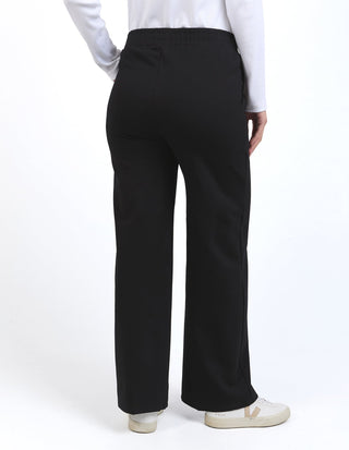 Back view of a woman wearing black wide leg pants and a white top.