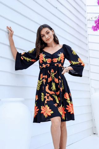 Woman wearing a black V-neck floral print summer dress with flared sleeves.