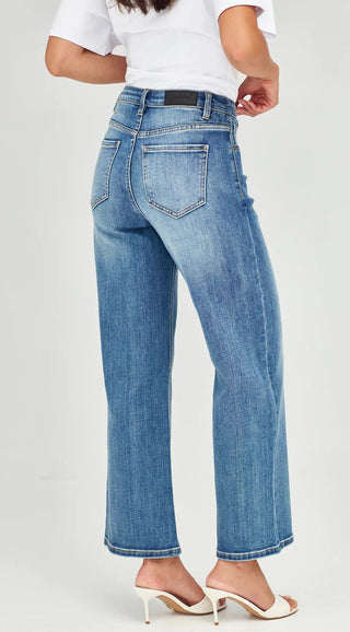Woman wearing blue high-waisted straight leg denim jeans and white heels.