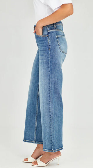 Woman wearing blue wide-leg denim jeans and white high-heeled sandals.