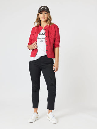 Woman wearing a red denim jacket, white graphic t-shirt, black ripped skinny jeans and white sneakers.