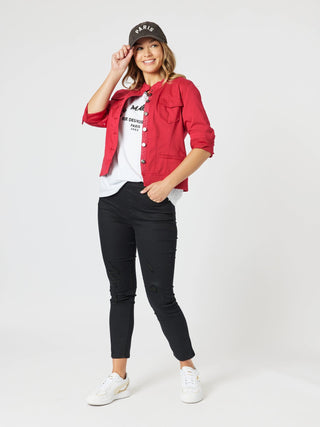 Woman wearing a red denim jacket, white t-shirt, black ripped jeans, and a Paris cap.