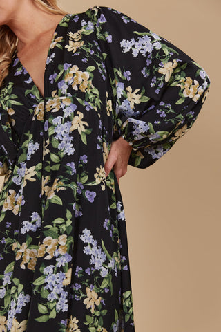 Woman wearing a black floral print dress with puff sleeves and a v-neckline
